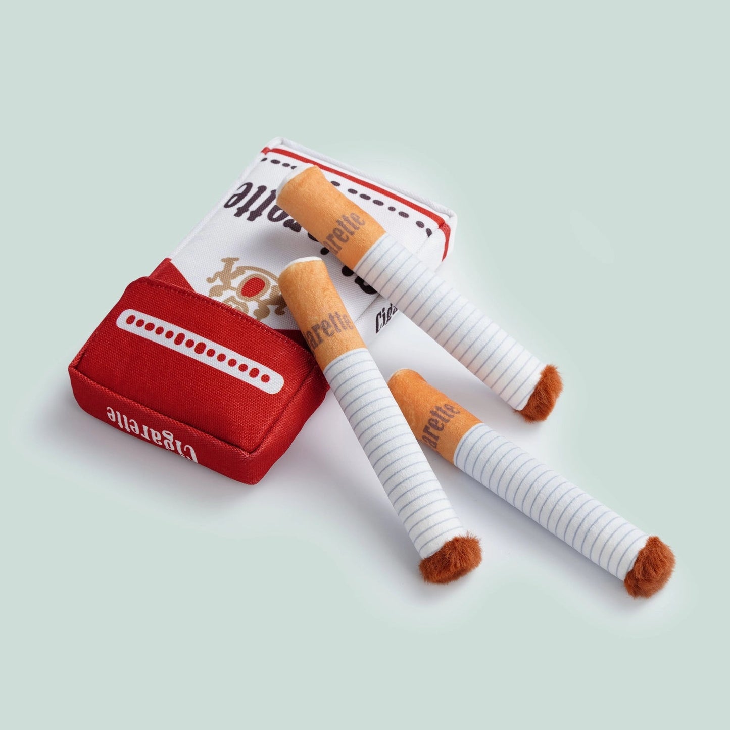 Nocciola Durable Giggle Toys for Puppies & Small to Medium Dogs by Nocciola include plush toy cigarettes and a plush pack, designed to look like real cigarettes but made of soft, durable fabric—perfect for tough chewers. Displayed on a light background.