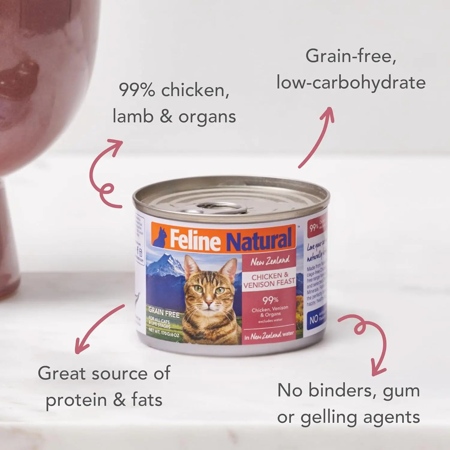 A can of Feline Natural Chicken & Venison Feast Grain-Free Canned Cat Food 12/6oz sits on a white surface, featuring labels for cage-free meats, grain-free, low-carb, and no binders or gums—packed with protein and healthy fats.