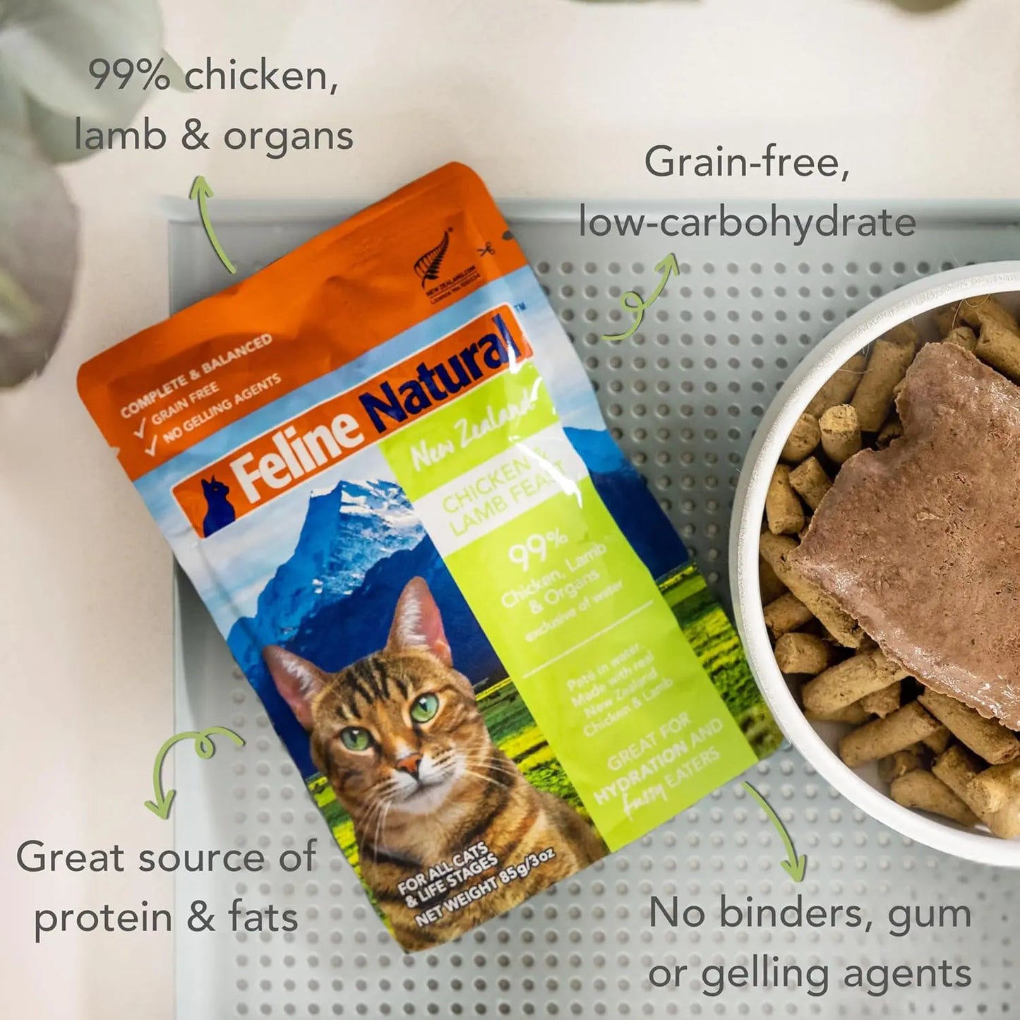 A pouch of Feline Natural Feast Grain-Free Wet Cat Food sits by a bowl of wet and dry food. Text highlights: 99% chicken, lamb & organs, grain-free, high-quality protein & fats, with no binders, gum, or gelling agents.