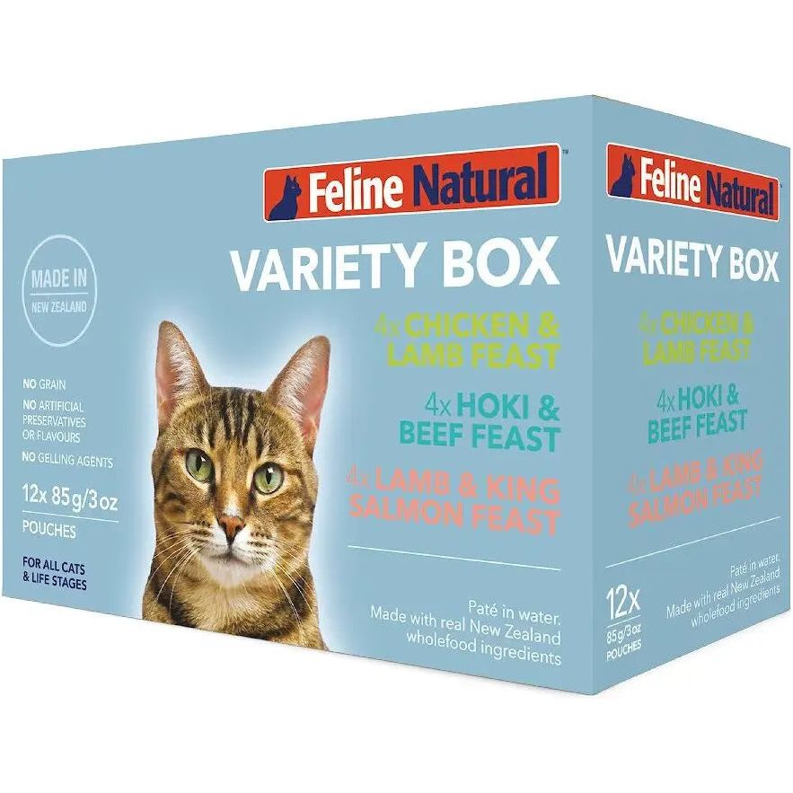 A box of Feline Natural Feast Grain-Free Wet Cat Food Pouch 12/3oz displays a close-up of a tabby cat. The pack includes cage-free chicken and free-range lamb flavors. Blue background highlights key product details.
