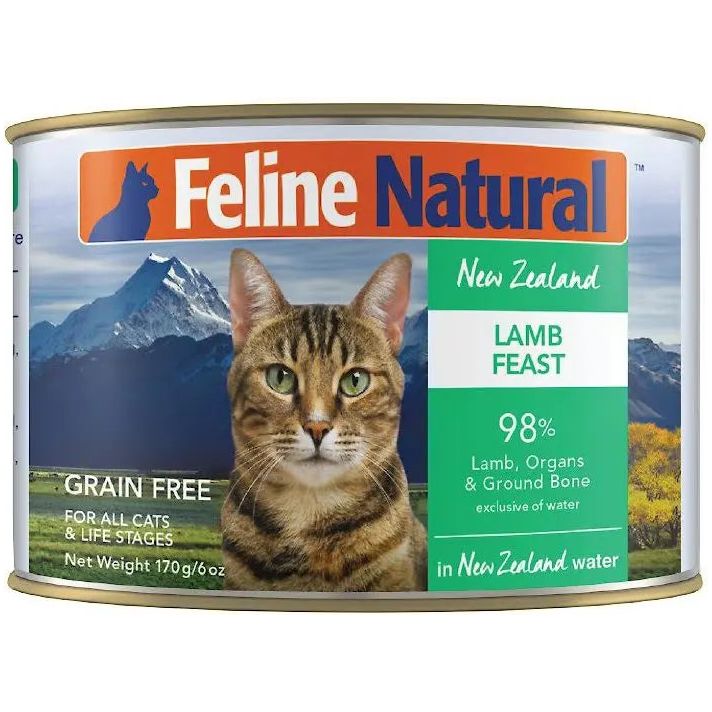 A can of Feline Natural Lamb Feast Grain-Free Canned Cat Food, featuring a tabby cat before a mountain scene. The label highlights 98% grass-fed lamb, organs, and ground bone for a wholesome meal. Brand: Feline Natural.