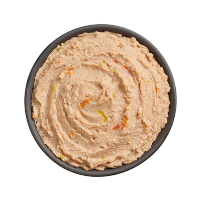 A black bowl filled with Petcurean Pet Foods Go! Solutions Booster Joint Care Chicken, Salmon & Duck Pate Wet Dog Food, a creamy light orange grain-free mix with veggie pieces, photographed from above on a white background.