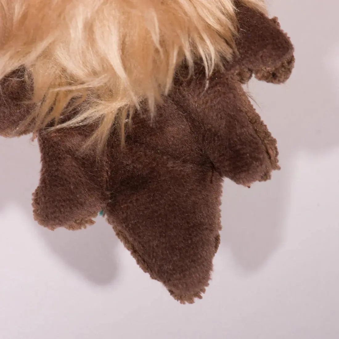 A close-up of the HuggleHounds Drake Duck X-Brace Tough Squeaky Plush Dog Toy’s brown paw, with tan fur above it, highlights this stuffed toy by HuggleHounds.