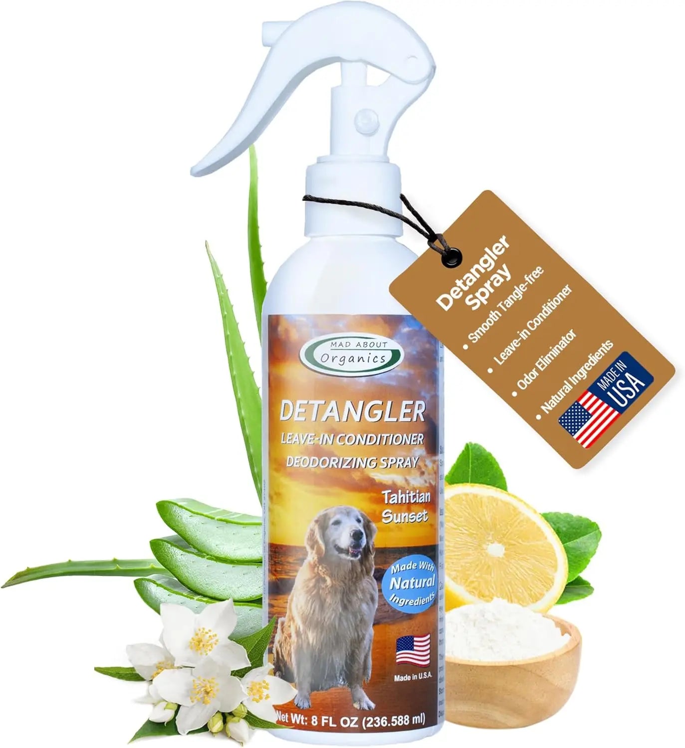 An 8oz Mad About Organics Detangler Spray bottle, with aloe leaves, lemon slice, and white flowers nearby. A tag notes all-natural pet conditioner benefits, while a US flag emphasizes American-made quality.