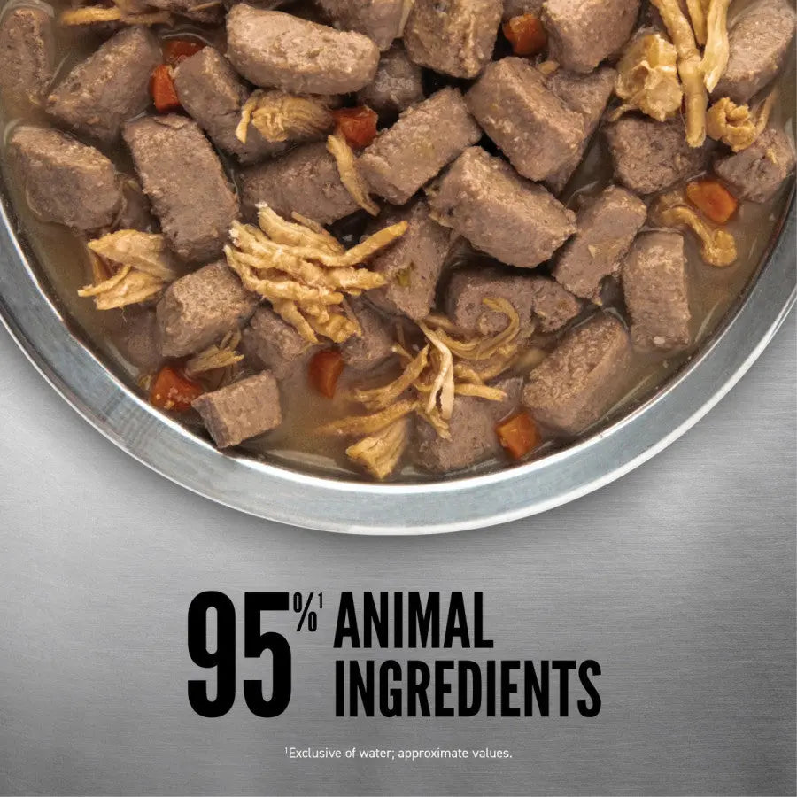 A close-up of a bowl filled with ORIJEN Real Meat Shreds Chicken, Turkey & Eggs Stew Grain-Free Wet Dog Food—meaty cubes and shreds in gravy. Text reads: 95% animal ingredients (excluding water). Brand: ORIJEN.