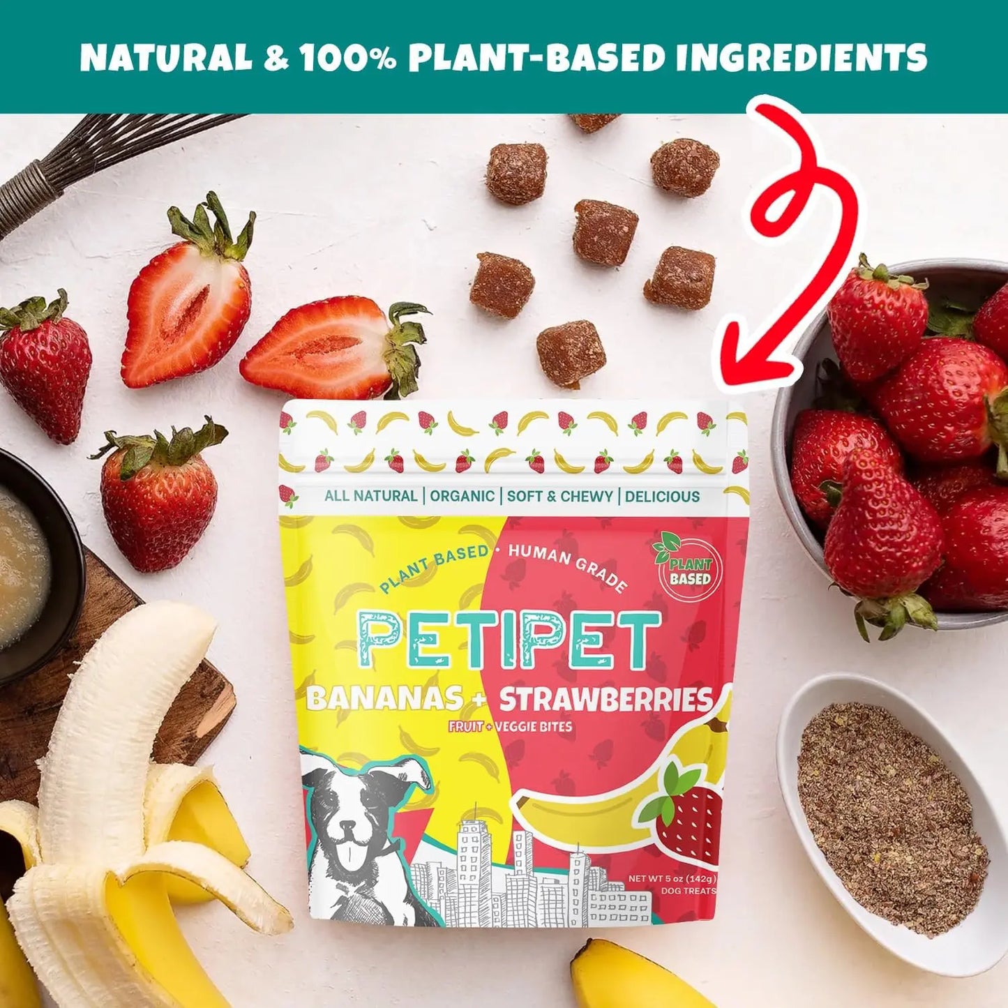A 5 oz bag of PETIPET Bananas + Strawberries Bites Soft & Chewy Dog Treats sits on a table with bananas, strawberries, flaxseed, and treats, highlighting their natural, limited ingredient recipe—100% plant-based for your pup.