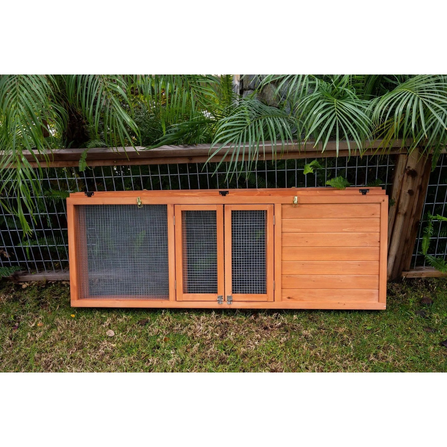 A Zoo Med Laboratories Easy-Fold Tortoise Terrarium Yard door with mesh panels sits on grass—perfect for outdoor tortoise enclosures—set before a wire fence and green plants.