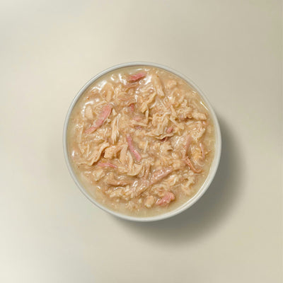 Petcurean grain free wet cat food in a bowl featuring shredded meat and a savory broth