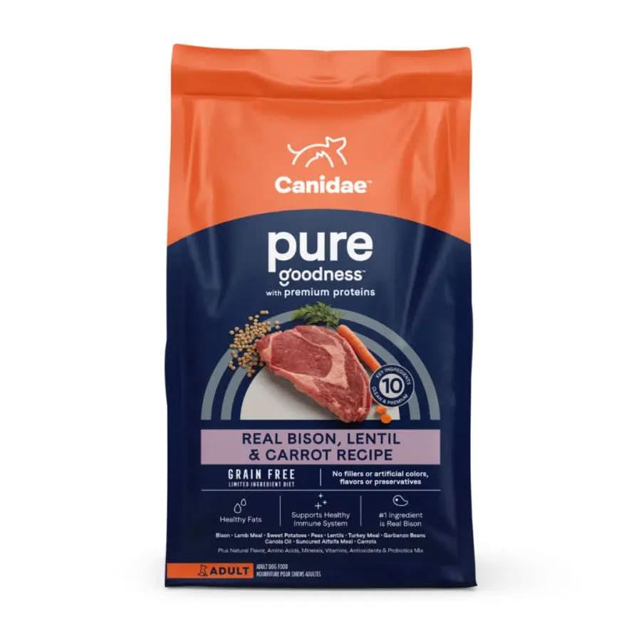 A bag of CANIDAE PURE Grain-Free Real Bison, Lentil & Carrot Recipe Dry Dog Food for adults, in orange and dark blue packaging with images of raw meat, lentils, and carrots on the front.