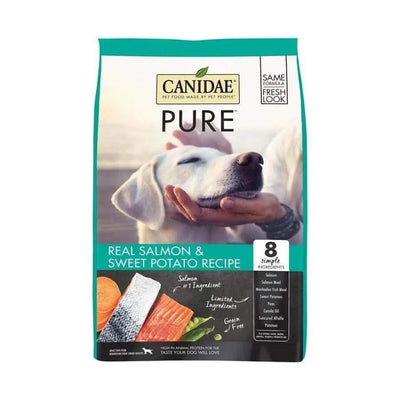 CANIDAE PURE Grain-Free Real Salmon & Sweet Potato Recipe Dry Dog Food features a white dog being gently held, with salmon and sweet potato images, and highlights limited ingredients for gentle nutrition.