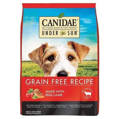A bag of CANIDAE Under The Sun Grain-Free Lamb Recipe Dry Dog Food shows a dog’s face and packaging with “Grain Free Recipe,” “Made with Real Lamb,” and images of farm-grown vegetables and lamb. Brand: CANIDAE.