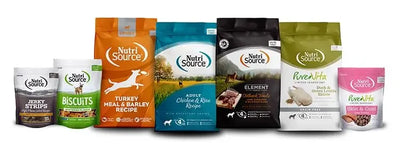 Bags of dog food, including turkey and jerky strips, displayed alongside a bag of biscuits with a dog image, all on a table.