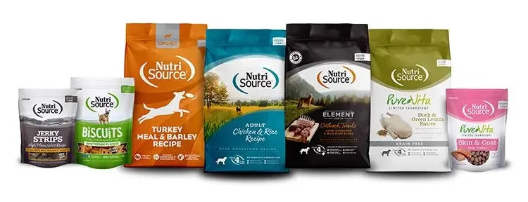 Bags of dog food, including turkey and jerky strips, displayed alongside a bag of biscuits with a dog image, all on a table.