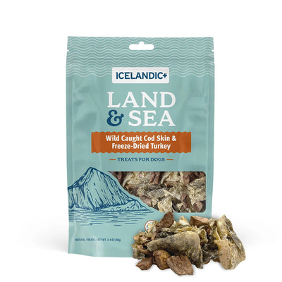 A teal bag of Icelandic+ Land & Sea Cod Skin & Freeze-Dried Turkey Dog Treats (2.4 oz) shows protein-rich treats, some scattered in front, with a mountain illustration at the bottom left and the Icelandic+ brand logo displayed.
