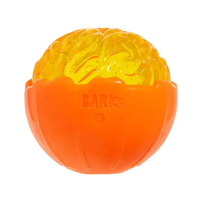 The BARK Pumpkin Prodigy Dog Chew Toy is an orange and yellow interactive toy shaped like a half-opened pumpkin with a brain design inside, featuring the word BARK and the letter M molded on its shell.