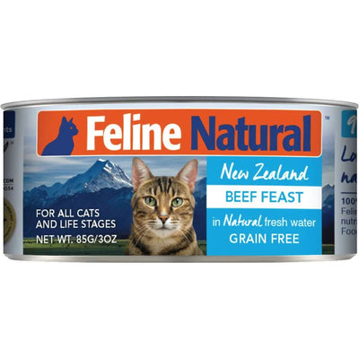 A can of Feline Natural Beef Feast Grain-Free Canned Cat Food, 85g/3oz, featuring a tabby cat and mountain backdrop. Label highlights wholefood ingredients; grain-free and suitable for all cats and life stages.