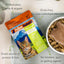A pouch of Feline Natural Feast Grain-Free Wet Cat Food sits by a bowl of wet and dry food. Text highlights: 99% chicken, lamb & organs, grain-free, high-quality protein & fats, with no binders, gum, or gelling agents.