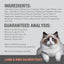A fluffy white and grey cat with blue eyes sits next to the Feline Natural Lamb & King Salmon Feast Grain-Free Canned Cat Food label, highlighting its quality ingredients, guaranteed analysis, safety, and recyclable packaging.