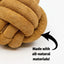 Close-up of the HuggleHounds HuggleHide Natural Leather Ball Dog Toy, featuring brown, suede-like natural leather with a black arrow and text: Made with all-natural materials! on a white background.
