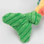 Close-up of a green, textured plush bird foot with visible stitching and ribbing, part of the HuggleHounds Raucous Rainbow Trout Knottie Tough Squeaky Plush Dog Toy. The multicolored plush toy’s edge appears in the background.