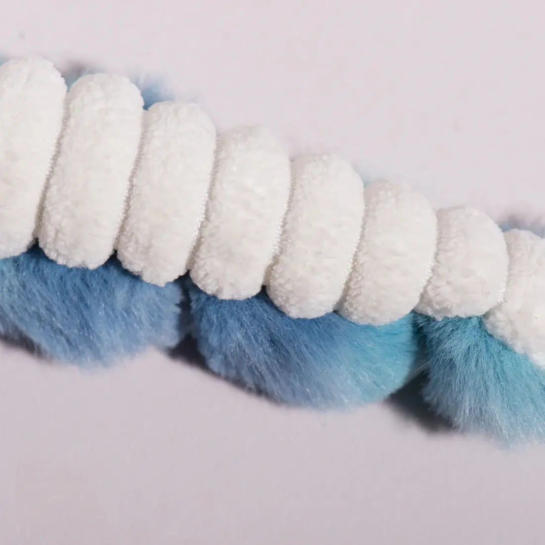 Close-up of the HuggleHounds X-Brace Calamaro Large Dog Tots, an interactive spiral dog toy by HuggleHounds, featuring alternating blue and white fluffy textures against a plain light background.
