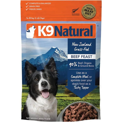 A bag of K9 Natural Beef Feast Raw Grain-Free Freeze-Dried Dog Food by K9 Natural, showing a black and white dog close-up with mountains behind and a bowl of freeze-dried food in front.