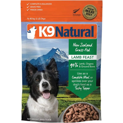 A bag of K9 Natural Lamb Feast Raw Grain-Free Freeze-Dried Dog Food with a black and white dog photo; highlights New Zealand grass-fed lamb, 90% lamb, organs & ground bone, and complete balanced nutrition. A bowl of kibble is shown.
