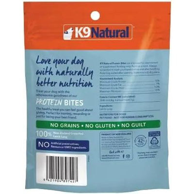 The K9 Natural Lamb Lung Protein Bites Air-Dried Dog Treats 2.1oz package features air-dried, grain- and gluten-free lamb lung treats. The orange and blue bag displays product info, nutritional details, and highlights No Guilt.