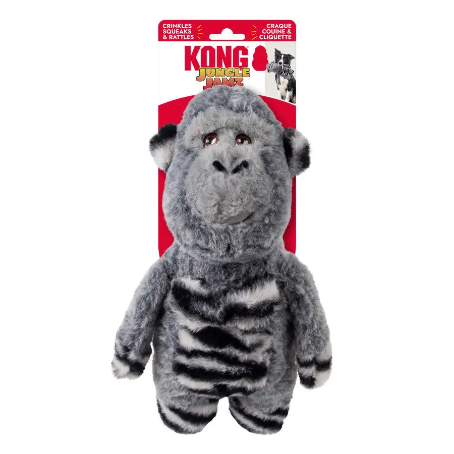 The KONG Jungle Jamz Gorilla Dog Toy by Kong is gray and black with a fluffy texture, brown embroidered eyes, a smiling face, and a durable squeaker, shown in front of red and white KONG Jungle Jamz packaging.