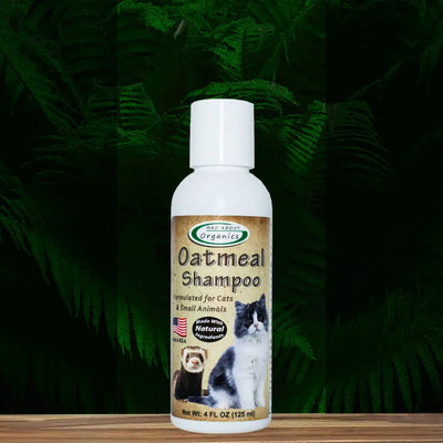 A 4oz bottle of Mad About Organics Cat Oatmeal Shampoo rests on wood, its label featuring a cat and ferret among ferns. This gentle, pH-balanced formula soothes cats and small animals skin for happier pets.