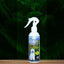 An 8oz bottle of Mad About Organics Detangler Spray—Knot-Free Coats Made Easy—resting on a wooden surface with green ferns. The label features a white dog and promotes its deodorizing detangler spray formula.