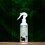 An 8oz bottle of Mad About Organics Detangler Spray—Knot-Free Coats Made Easy—with a deodorizing cedarwood scent, dog on the label, and trigger nozzle is displayed against a dark green fern background.