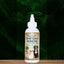 A white bottle of Mad About Organics Herbal Gel for Pet Oral Care with a pointed nozzle and cat and dog images on the label stands on wood, green foliage behind. Made by Mad About Organics with natural ingredients and a no-brush formula.