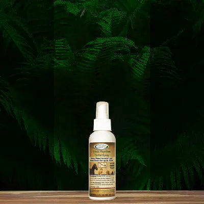 A bottle of Mad About Organics Herbal Spray – Natural Bug Repellent for Pets by Mad About Organics rests on a wooden surface with green ferns in the background. The label shows a horse and dog, emphasizing natural bug protection ingredients.