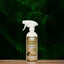 A spray bottle of Mad About Organics Herbal Spray – Natural Bug Repellent for Pets sits on a wooden surface among green ferns, with a label featuring a horse and dog and its natural insect repellent benefits.