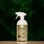 A white spray bottle of Mad About Organics Herbal Spray – Natural Bug Repellent for Pets rests on a wooden surface with leafy ferns behind it. Its beige label displays animal silhouettes and green text highlighting safe, natural ingredients.