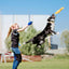 A girl tosses the Nocciola Durable Duck Squeaky Dog Toy for Aggressive Chewers, while a black and white dog leaps to catch it in a grassy outdoor field on a sunny day.