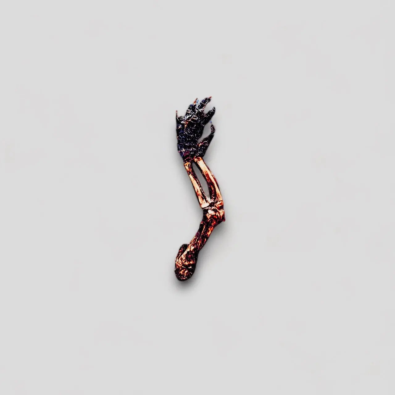 A small, sculpted human arm and hand resembling the unique texture of Mosaic Nutrigator® Farm-Raised Alligator Feet Hypoallergenic Dog Treats Bulk rest isolated on a plain gray background, appearing charred or heavily damaged.
