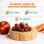 PETIPET Apples + Carrots Bites Soft & Chewy Dog Treats (5 oz) from PETIPET are plant-based, grain-free snacks with no fillers or artificial preservatives. Shown on a wooden board with apple and carrots in the background.