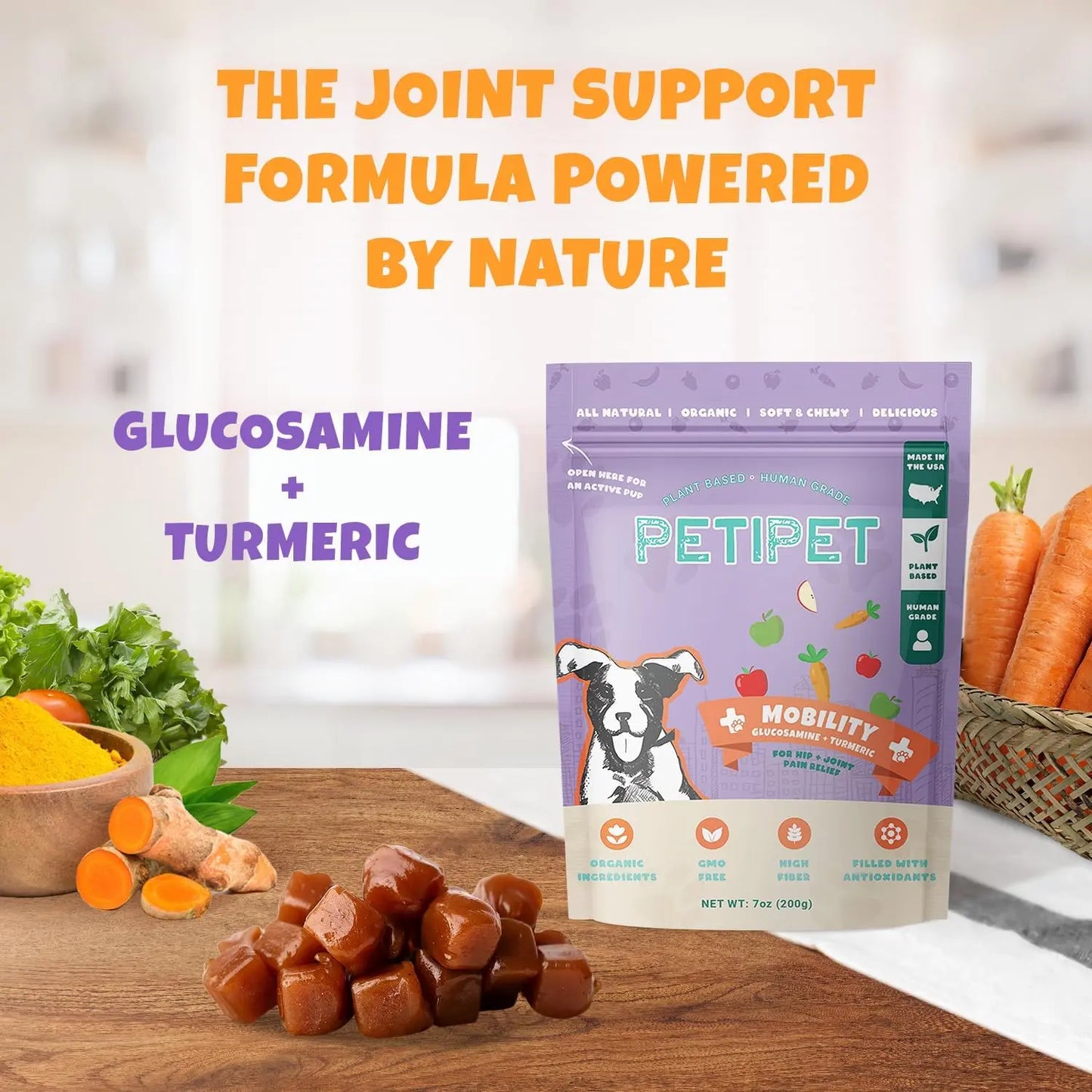 A bag of PETIPET Mobility Bites with Glucosamine + Turmeric Apple & Carrot Flavored Soft Chew Hip & Joint Supplement for Dogs 7oz sits on a table with turmeric, glucosamine capsules, lettuce, and carrots. Text highlights Glucosamine + Turmeric joint support.