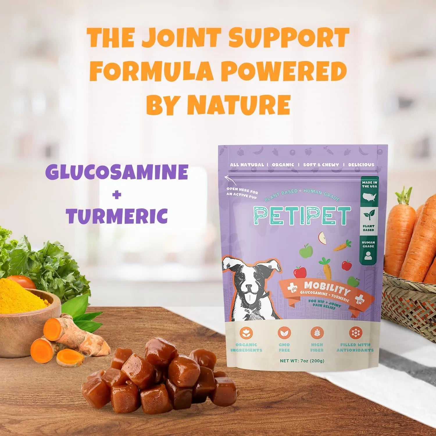 A bag of PETIPET Mobility Bites with Glucosamine + Turmeric Apple & Carrot Flavored Soft Chew Hip & Joint Supplement for Dogs 7oz sits on a table with turmeric, glucosamine capsules, lettuce, and carrots. Text highlights Glucosamine + Turmeric joint support.