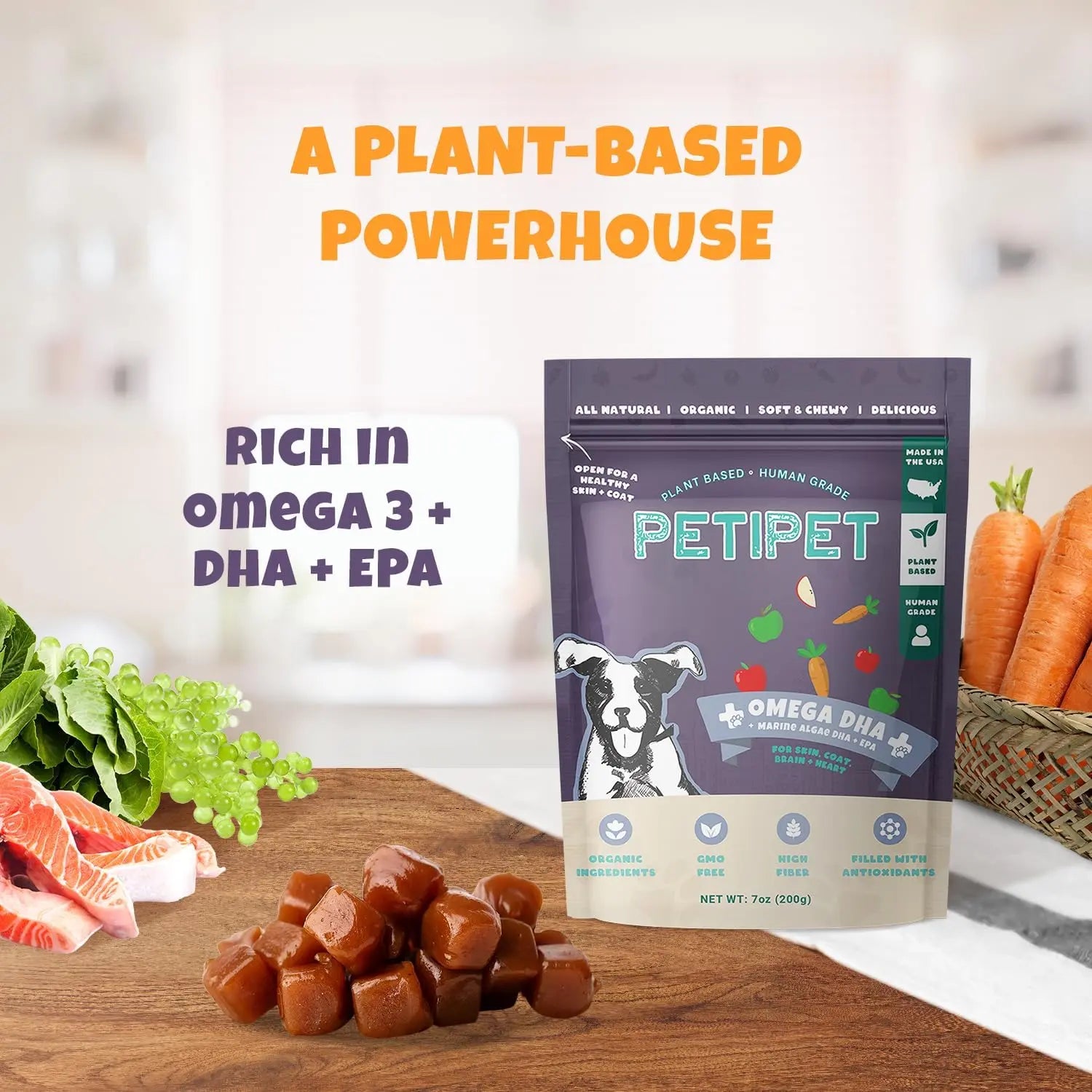 A bag of PETIPET Omega DHA Bites with Marine Algae DHA + EPA Apple & Carrot Flavored Soft Chews for Dogs sits on a kitchen counter amid veggies, salmon, and grapes. Text reads “A Plant-Based Powerhouse” and “Rich in Omega 3 + marine algae DHA.”.