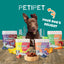 A happy brown dog sits behind four bags of PETIPET Pumpkin Fruit + Veggie Bites Gluten-Free Adult Soft & Chewy Dog Treats—made with human-grade ingredients and surrounded by fresh produce. Text reads PETIPET Your Dogs Delight.