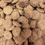 A close-up of many round, brown Poochie Butter Cheezy Soft Chewy Dog Treats, featuring a rough texture and arranged closely together.
