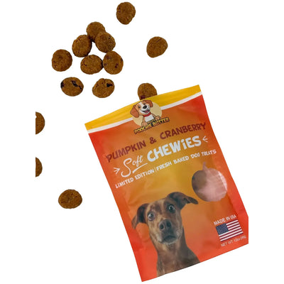 An open bag of Poochie Butter Dillys Pumpkin Soft & Chewy Dog Treats 12oz shows round treats scattered nearby. The Poochie Butter bag features a playful dog face and bright colors—perfect pumpkin dog treats for your pup.