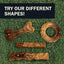 Four Redbarn Hickory BBQ Dur-A-Bulls Bone chews lie on green grass. Above them, a bold sign reads: TRY OUR DIFFERENT SHAPES! Enjoy limited-ingredient Redbarn treats for a healthier dog chew choice.