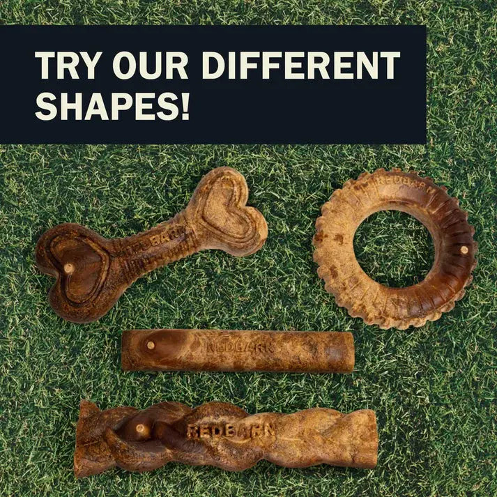 Four Redbarn Hickory BBQ Dur-A-Bulls Bone chews lie on green grass. Above them, a bold sign reads: TRY OUR DIFFERENT SHAPES! Enjoy limited-ingredient Redbarn treats for a healthier dog chew choice.