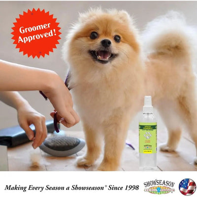 A fluffy Pomeranian gets groomed with scissors and a brush. In the foreground is Showseason Lavender Flowers Pet Cologne, an eco-friendly spray. Text reads: Groomer Approved! Making Every Season a Showseason® Since 1998.
