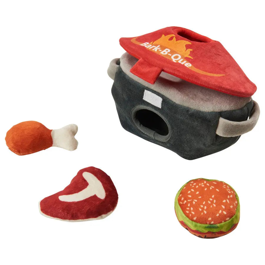 The Spot Grill Time Puzzle Dog Toy by Spot features a soft red barbecue grill with a hole and three plush food pieces—a drumstick, steak, and hamburger—for interactive brain training fun. All items are made from soft fabric.