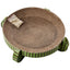 The Spot Nest Cat Scratcher by Spot is a round cardboard scratcher with green zigzag sides, designed to support nail health. It includes a catnip packet on the surface and stands on four short legs.
